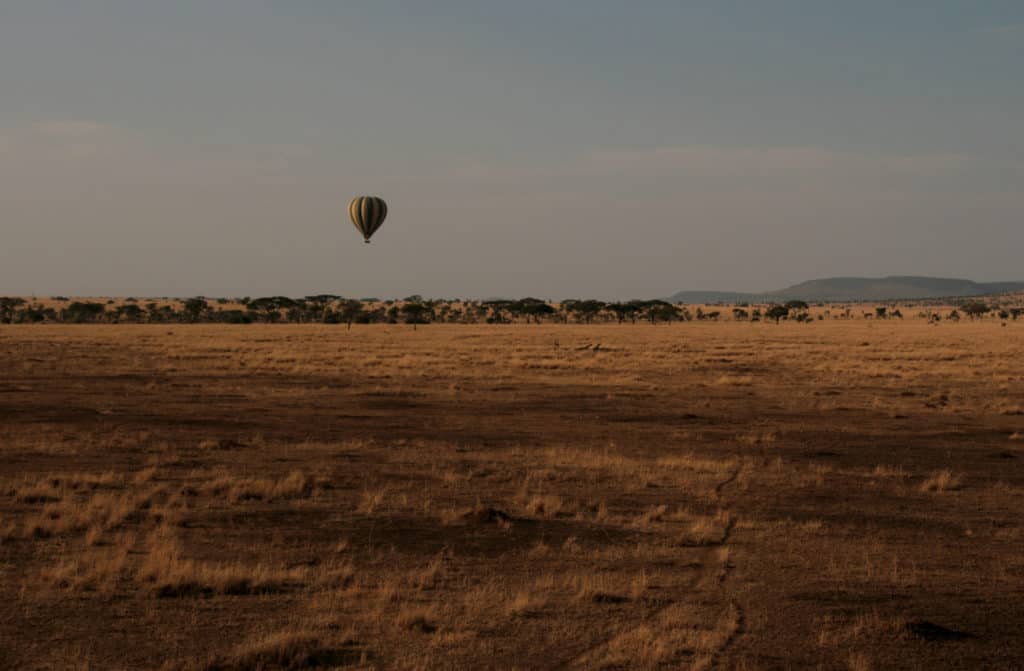 Hot air Balloon in distance soaring over the Serengeti plains on a balloon safari in Africa
