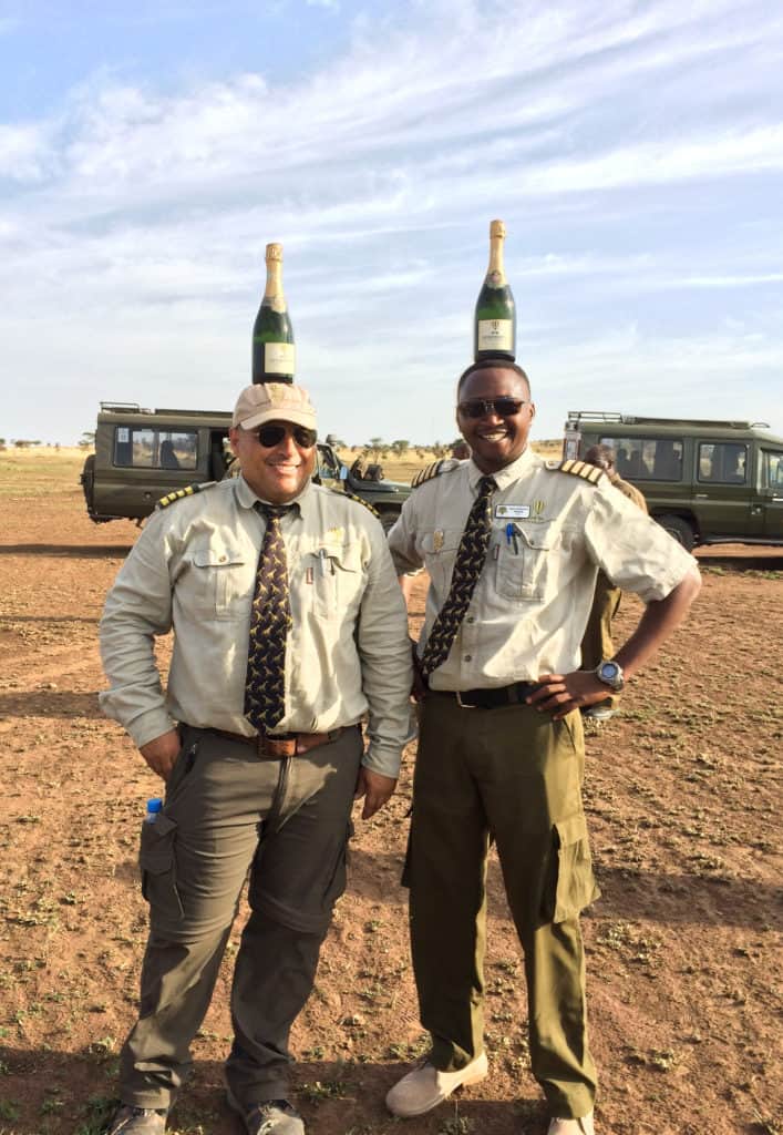 Hot air balloon pilots with champagne on their head in the Serengeti in Tanzania in Africa