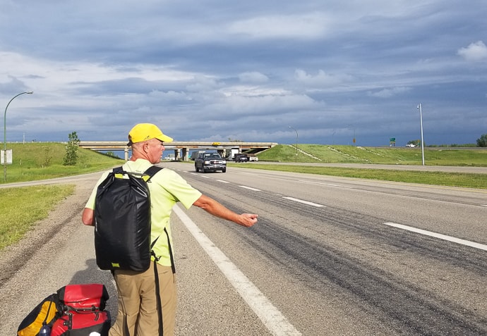 Matt standing with his thumb out in Canada while hitchhiking