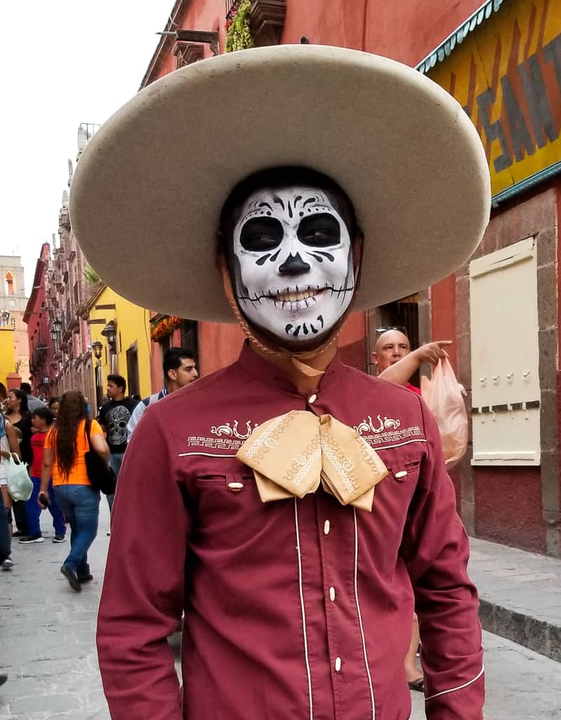 Man with face painted for day of the dead wearing a large hat