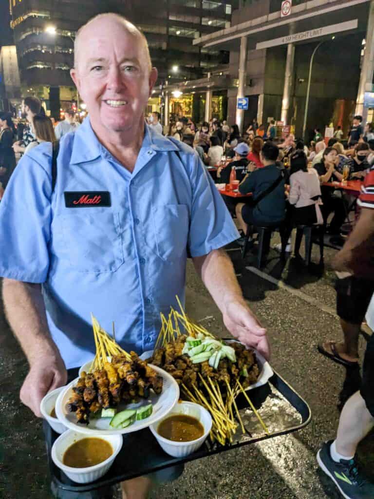 Matt carrying a large tray of Chicken Satay