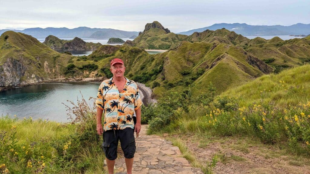 Man standing on top of a mountain with ocean behind him