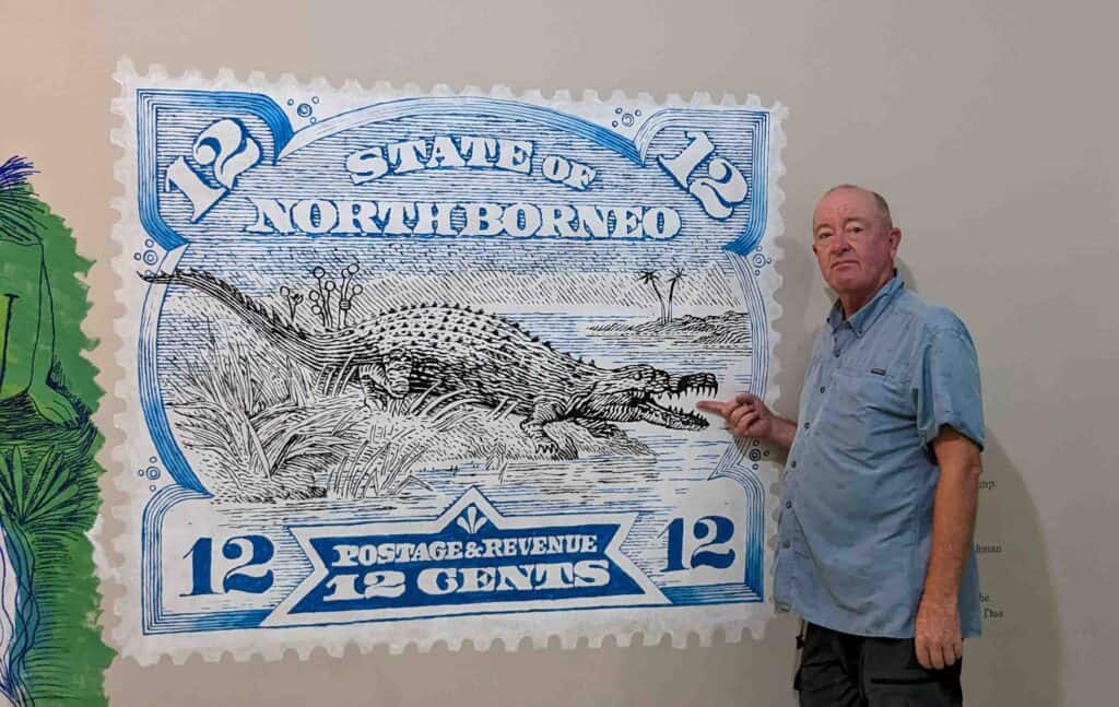 Man standing beside a large postage stamp