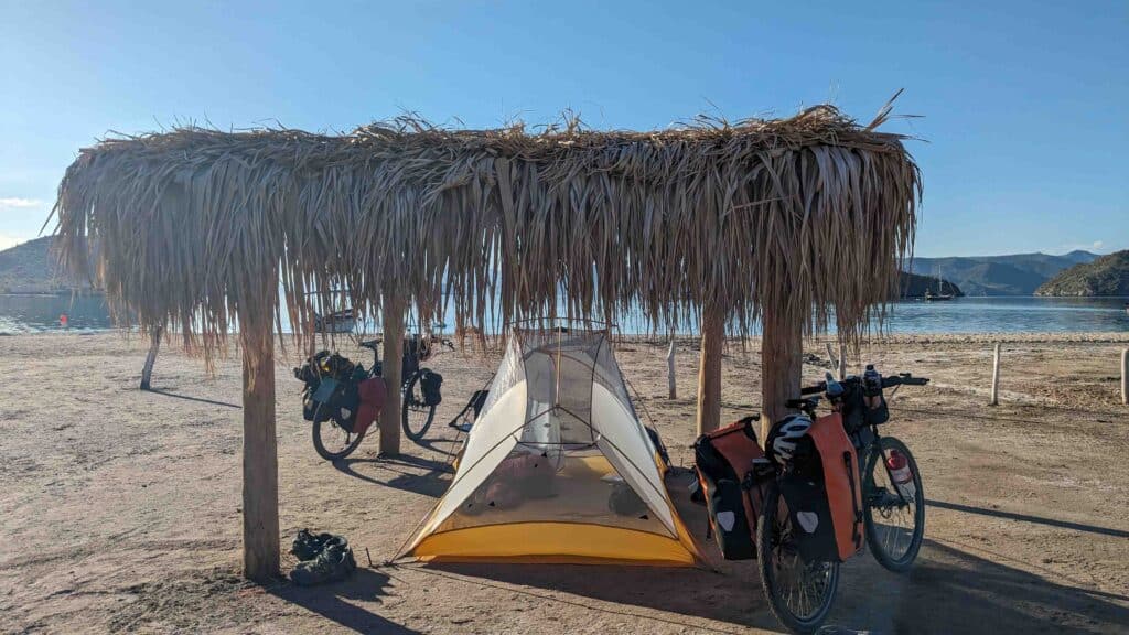 tent, two bicycles and a palapa on a beach